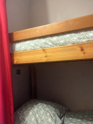 Ein Stockbett mit gemustertem Matratze und einem Holzkopfstück.