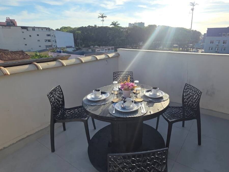A round table with four chairs on a rooftop terrace with a city view.