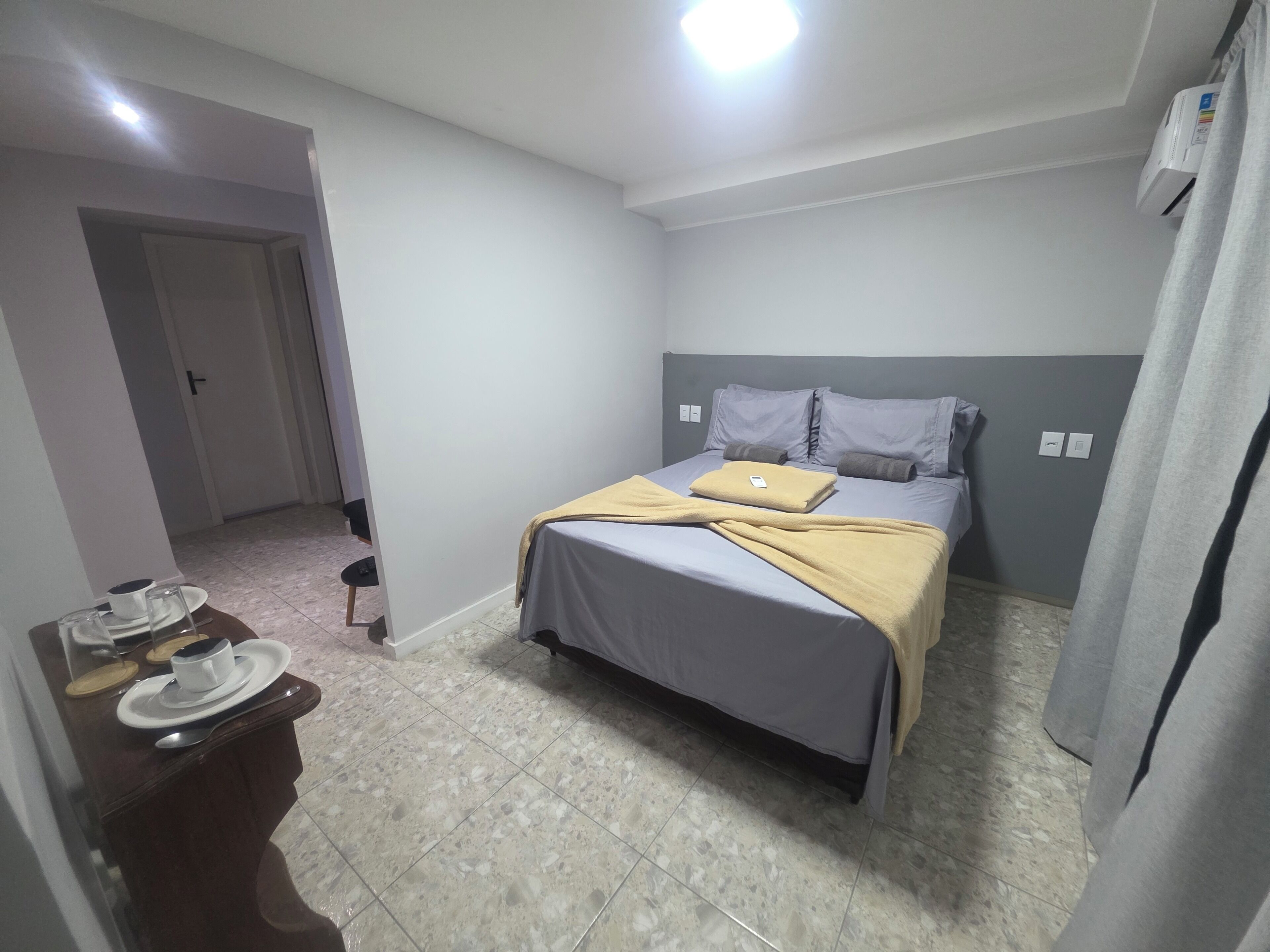A bedroom with a bed, a bedside table, a chair, and a door.