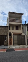 A two-story building with a stone facade, a wooden gate, and a closed garage door.