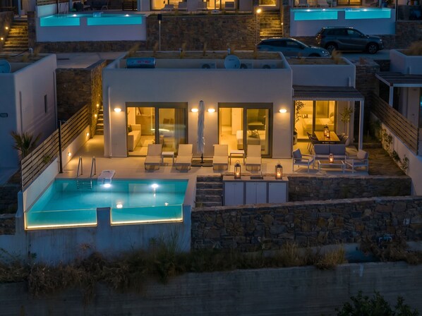 Una villa moderna con piscina, mobiliario exterior y fachada de piedra.