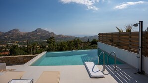 Una piscina con vista sulle montagne, una recinzione in legno e un corrimano in metallo.