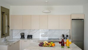 Una cucina moderna con piani in marmo, un'isola centrale con frutta e bevande, e un frigorifero in acciaio inossidabile.
