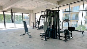 Ein Fitnessstudio mit unterschiedlichen Trainingsgeräten, großen Fenstern und Blick nach draußen.