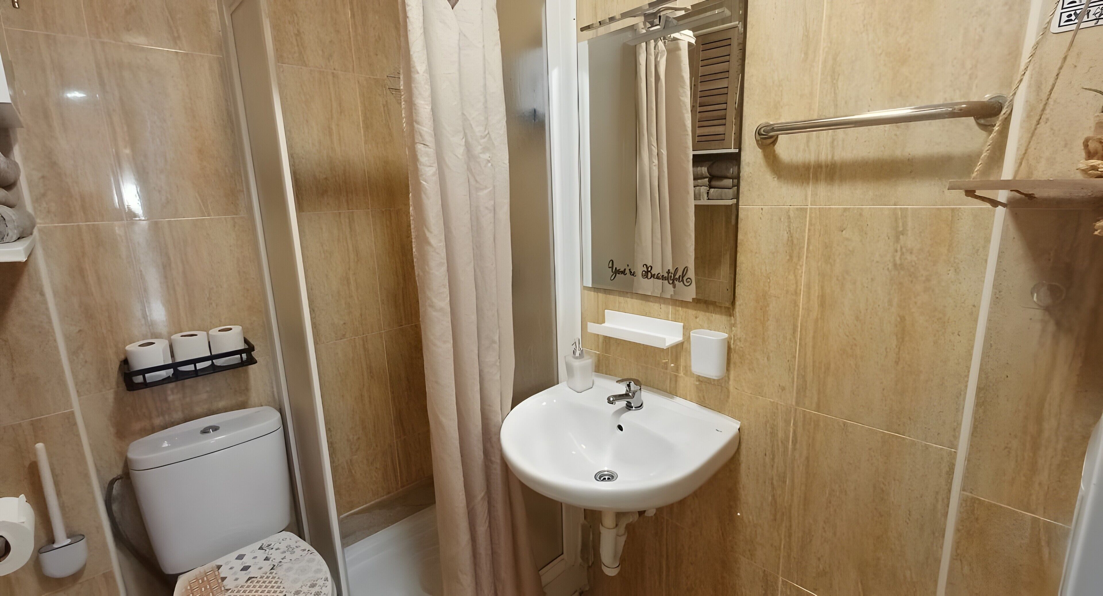 A bathroom with a toilet, sink, and shower curtain.
