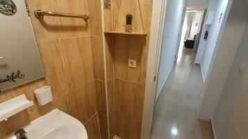 A bathroom with a bathtub, a towel rack, a shelf with a plant, and a sign on the wall.
