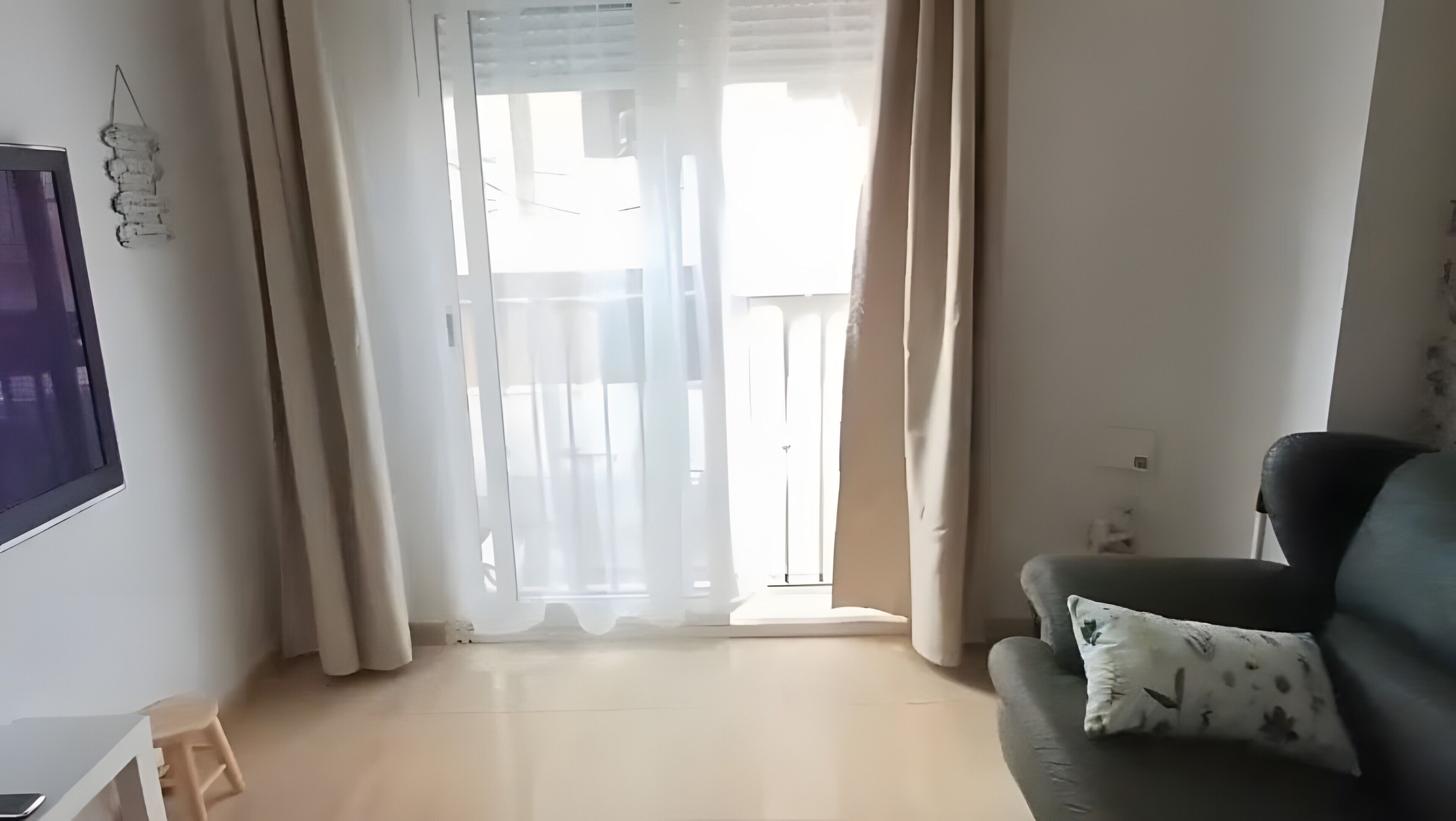 A living room with a sofa, a TV, and a sliding glass door.