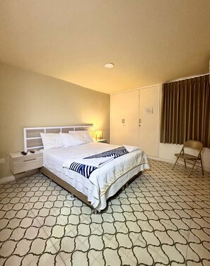 Een hotelkamer met een bed, nachtkastjes, een kledingkast en een stoel.