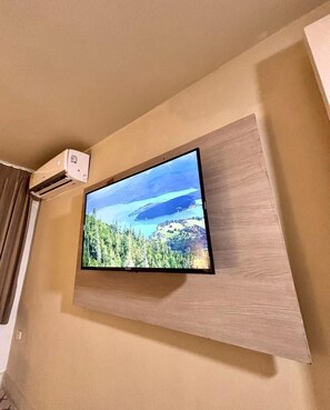 Een televisie bevestigd aan een muur, met een houten paneel eronder.
