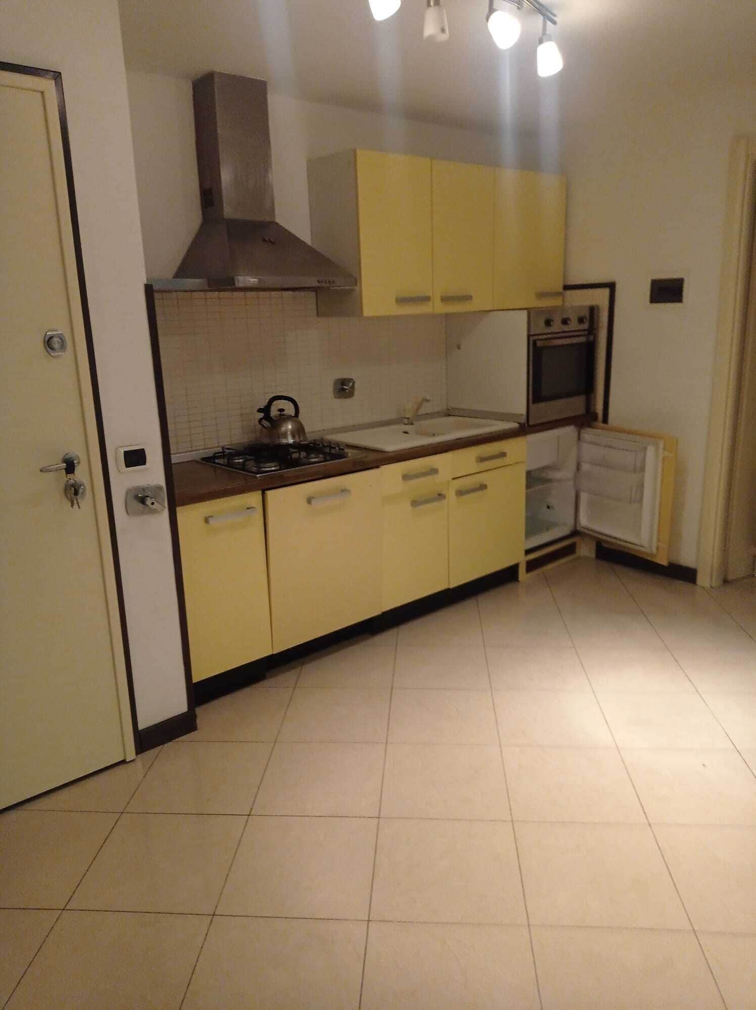 A compact kitchen with a gas stove, a kettle, a sink, and a built-in oven.