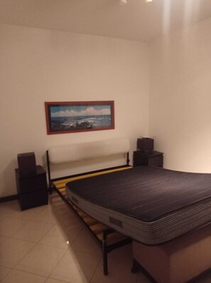 A bedroom with a bed, a nightstand, a dresser, and a wall-mounted picture. - Only 3 minutes' walk from the Blue sea, train, bus, supermarket, & coffee shops. (Bordighera)