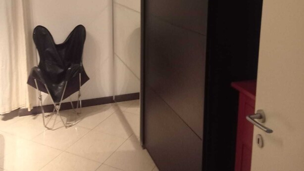 A room with a sliding door, a chair, and a red cabinet.
