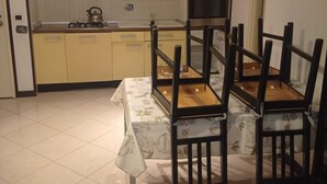 A dining area with a table set for four, a kitchen with yellow cabinets, and a stove.