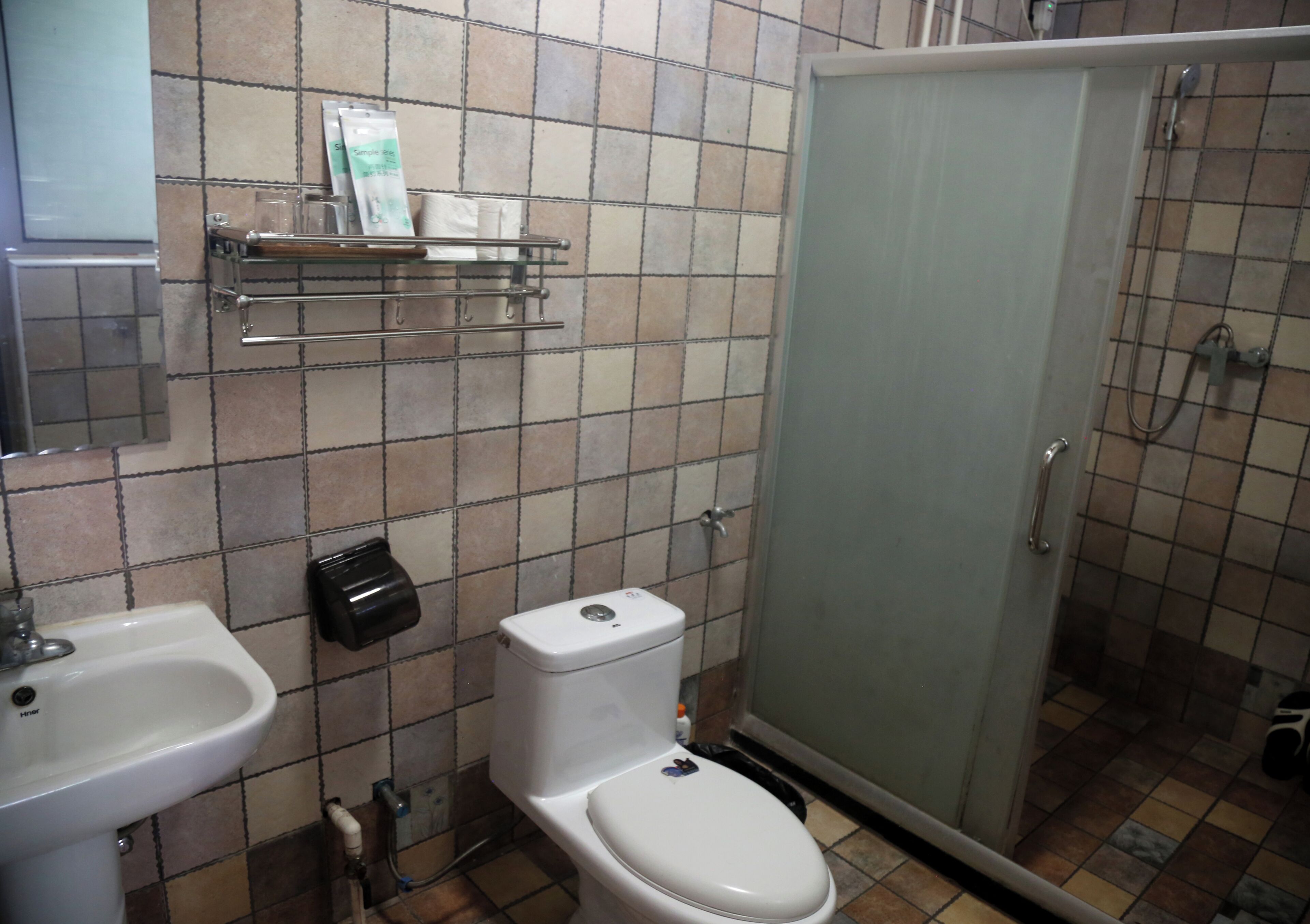 Et badeværelse med toilet, vask og bruser.