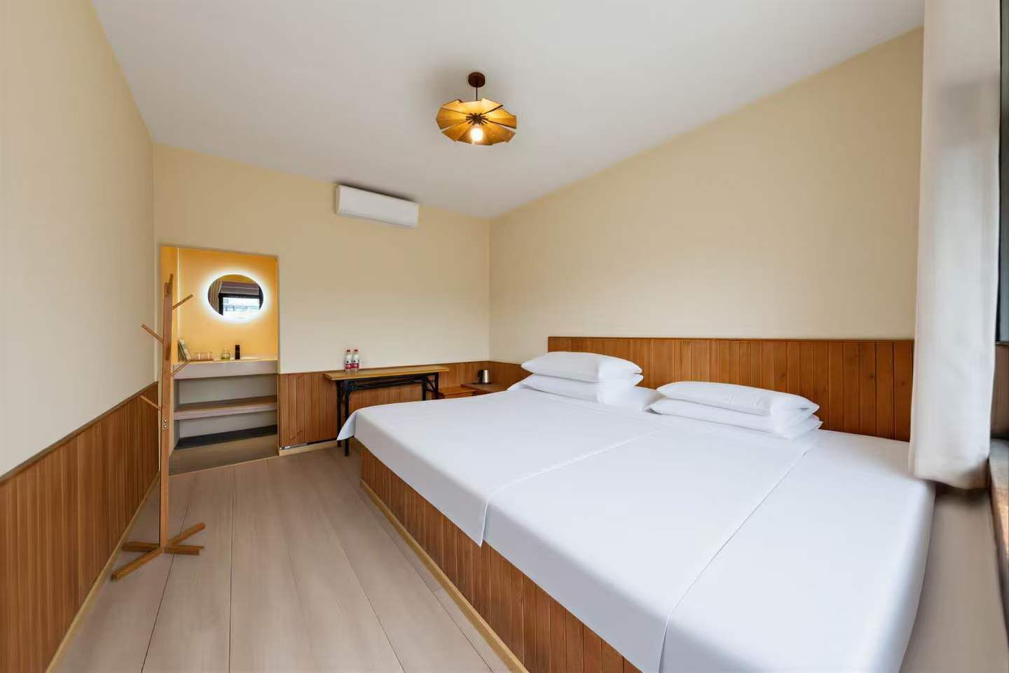 Ett hotellrum med en säng, ett sängbord, en spegel och en taklampa.