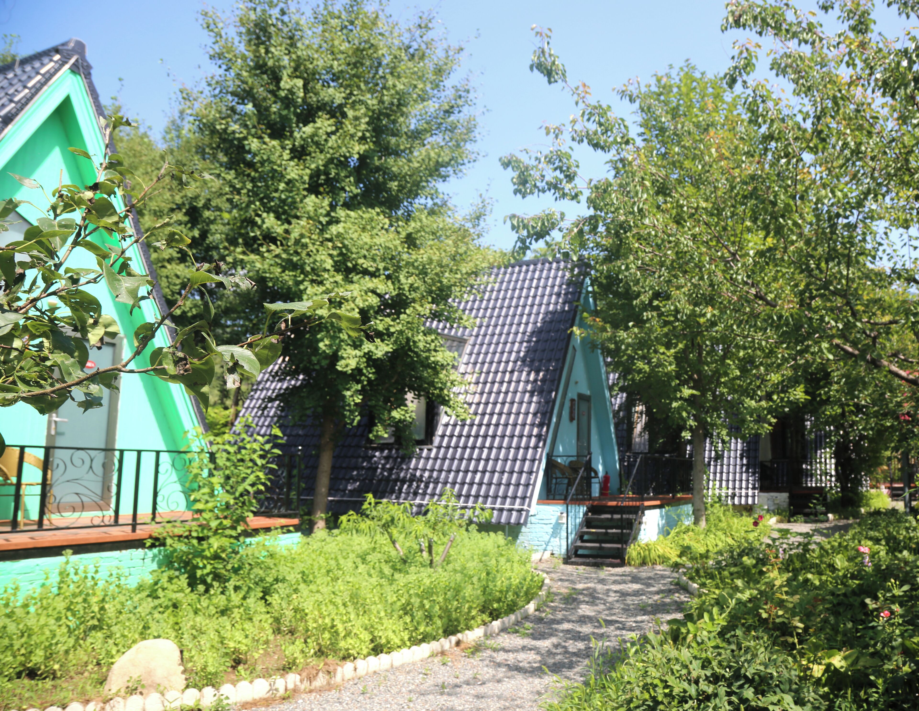A pathway leading to a building with a steeply pitched roof and a small staircase.