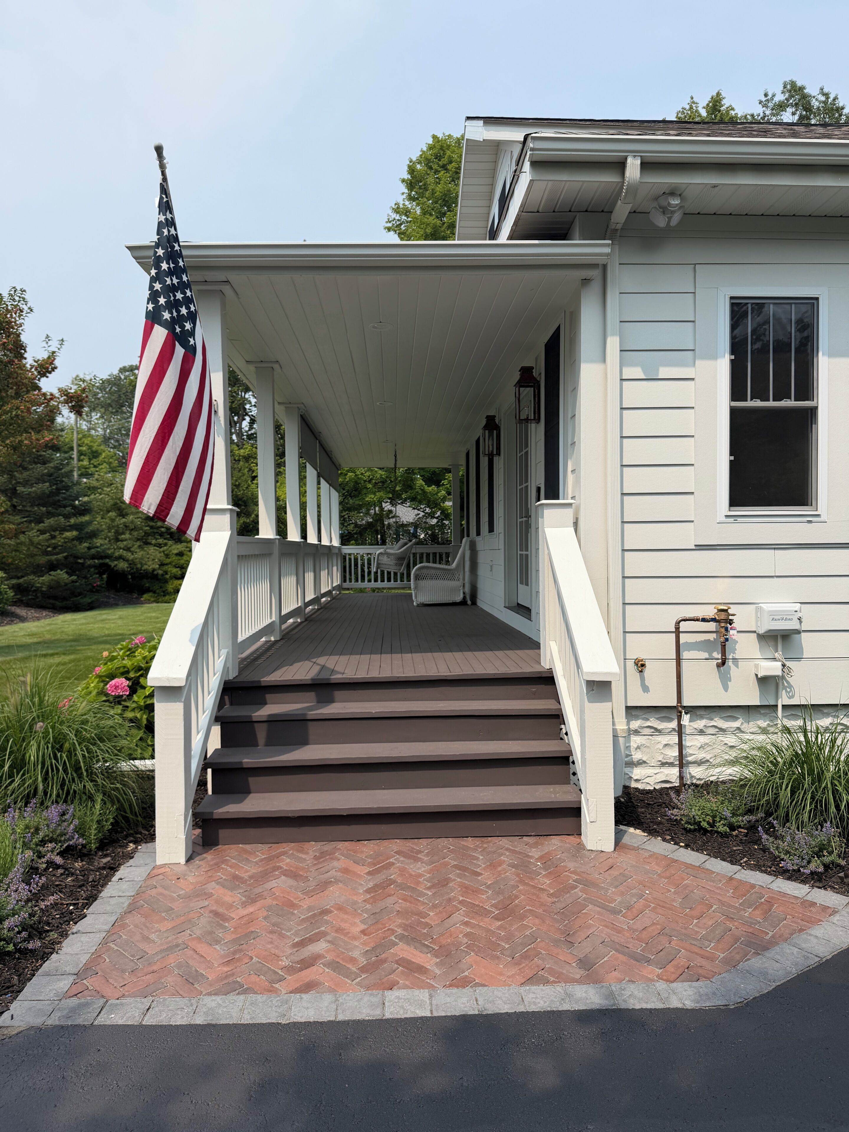 A house with a covered porch, steps leading to the entrance, and an American flag.