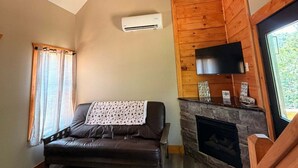 Ein gemütliches Wohnzimmer mit einer Couch, einem Kamin, einem Deckenventilator und einem Fernseher.