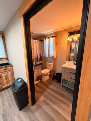 Et badeværelse med toilet, vask og bruseforhæng.