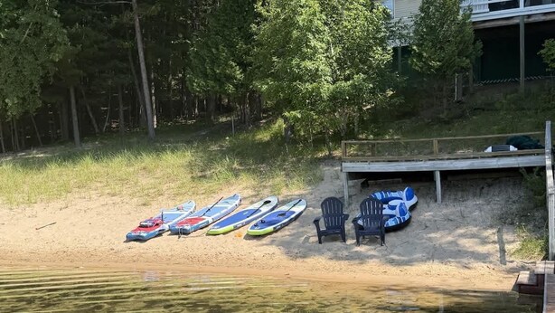 Een zandstrand met meerdere paddleboards en stoelen.