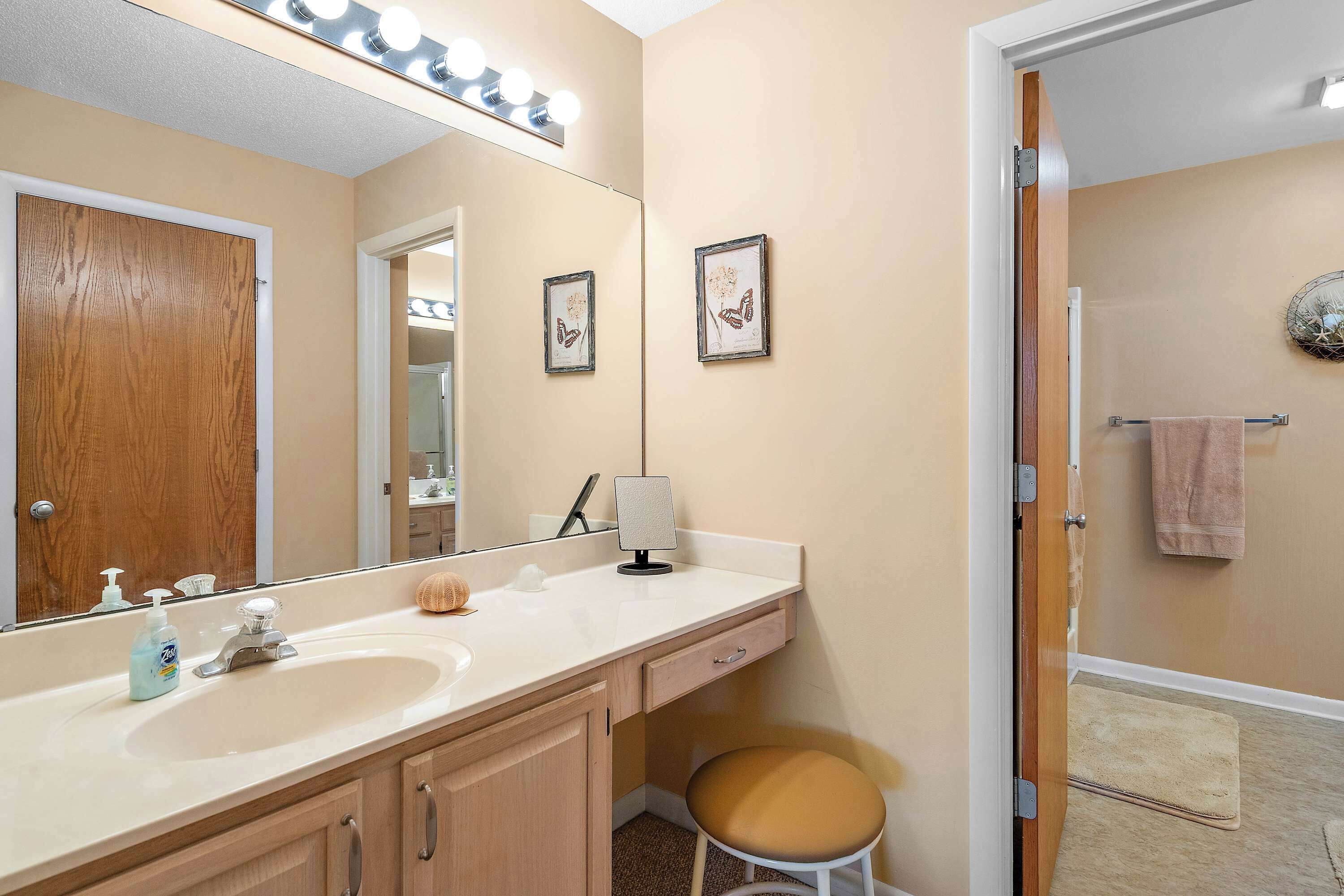 A bathroom with a vanity, sink, mirror, and a towel rack.