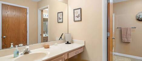 A bathroom with a vanity, sink, mirror, and a towel rack.