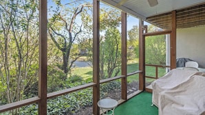 A room with a view of a garden, a ceiling fan, and a table with a covered tablecloth. - Eagle Way 2 - Access to Pools (Rehoboth Beach)
