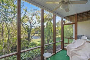 Ein Zimmer mit Blick auf einen Garten, einem Deckenventilator und einem Tisch mit einer Tischdecke.