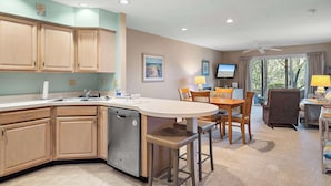 A kitchen with wooden cabinets, a dishwasher, a dining area with a table and chairs, and a ceiling fan. - Eagle Way 2 - Access to Pools (Rehoboth Beach)