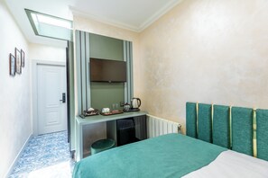 Habitación de hotel con cama, escritorio con televisor de pantalla plana, radiador y ventana con vistas.