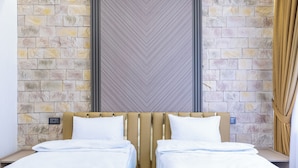 A double bed with a headboard against a stone wall, a power outlet, and a curtain on the right. - Runa Hotel Baku (Baku)