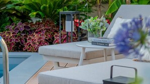 A poolside area with lounge chairs, a small table with a book, and a lantern. - The Secret Garden Cottage (Lucca)