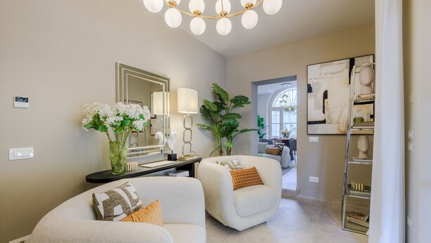 A modern living room with a sofa, a coffee table, a large mirror, and a chandelier. - The Secret Garden Cottage (Lucca)