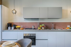Eine moderne Küche mit einem Gasherd, einer Kaffeemaschine und frischem Obst und Gemüse auf der Arbeitsfläche.