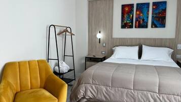 Una habitación de hotel con cama, una silla, una mesita de noche y decoración en la pared.