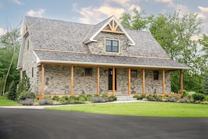 A stone house with a gabled roof and a covered porch.