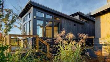 A modern two-story building with large windows and a wooden deck.