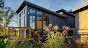 A modern two-story building with large windows and a wooden deck.