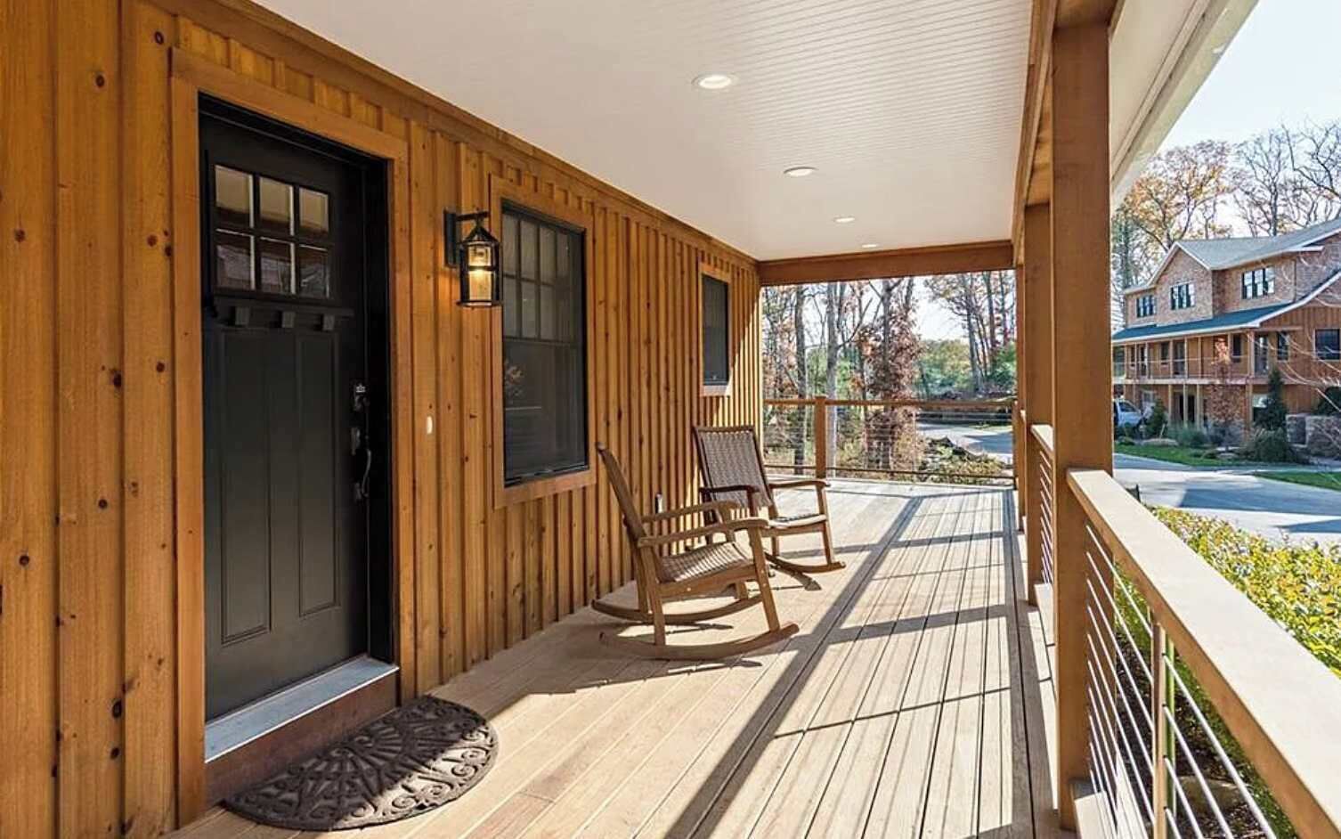 A wooden exterior with a porch, two rocking chairs, and a door with windows.