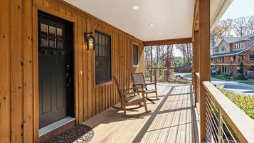 A wooden exterior with a porch, two rocking chairs, and a door with windows.