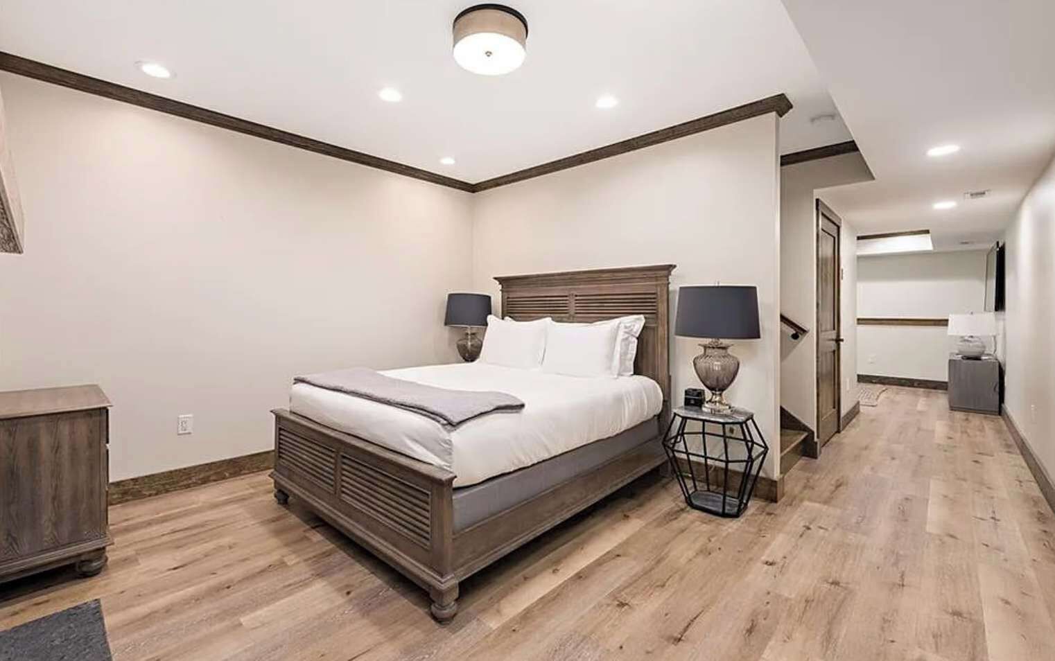 Un dormitorio con cama, lámparas de noche, cabecero de madera y mesita de noche.