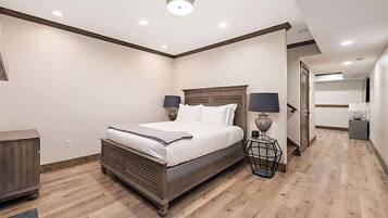 Un dormitorio con cama, lámparas de noche, cabecero de madera y mesita de noche.