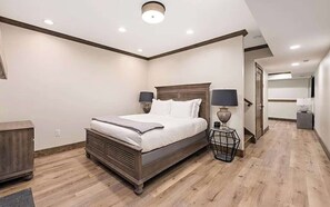 A bedroom with a bed, bedside lamps, a wooden headboard, and a nightstand. - Laurel Ridge | Three Bedroom Grand (Richmond)