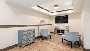 Une chambre d’hôtel avec un plancher en bois, une armoire bleue, deux chaises, un téléviseur et un luminaire au plafond.