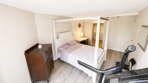Ein Schlafzimmer mit Himmelbett, Schreibtisch und Stuhl sowie einem Kleiderschrank.
