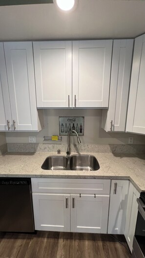 A kitchen with white cabinets, a stainless steel sink, and a dishwasher. - Peaceful retreat with city views (San Diego)
