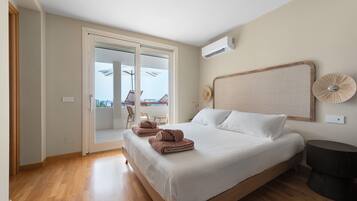 A bedroom with a bed, a sliding glass door leading to an outdoor area, a ceiling fan, and a wall-mounted air conditioning unit.