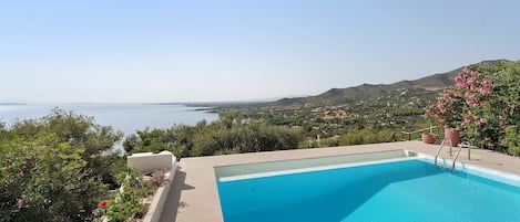 A swimming pool with a view of the sea and hills.