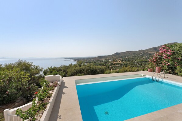 A swimming pool with a view of the sea and hills.