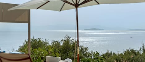 Un espacio de estar al aire libre con vista al mar y un barco a lo lejos.